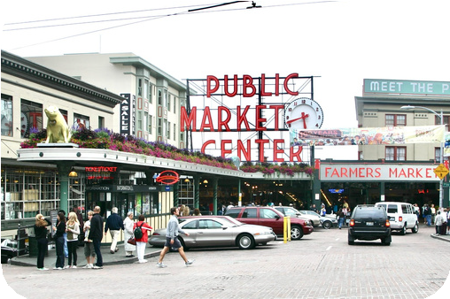 A group of people walking in front of a market with Pike Place Market in the backgroundAI-generated content may be incorrect.